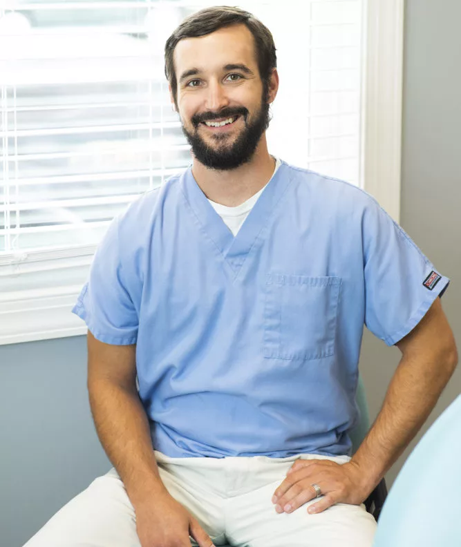 Dr. Jon Byrd of High Point Dental Partners smiling sitting down with hand on leg