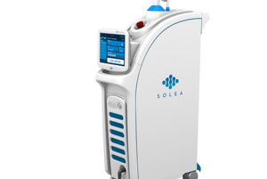 Medical device labeled 'SOLEA' with a screen interface and red emergency stop button, used for laser treatments.