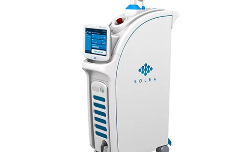 Medical device labeled 'SOLEA' with a screen interface and red emergency stop button, used for laser treatments.